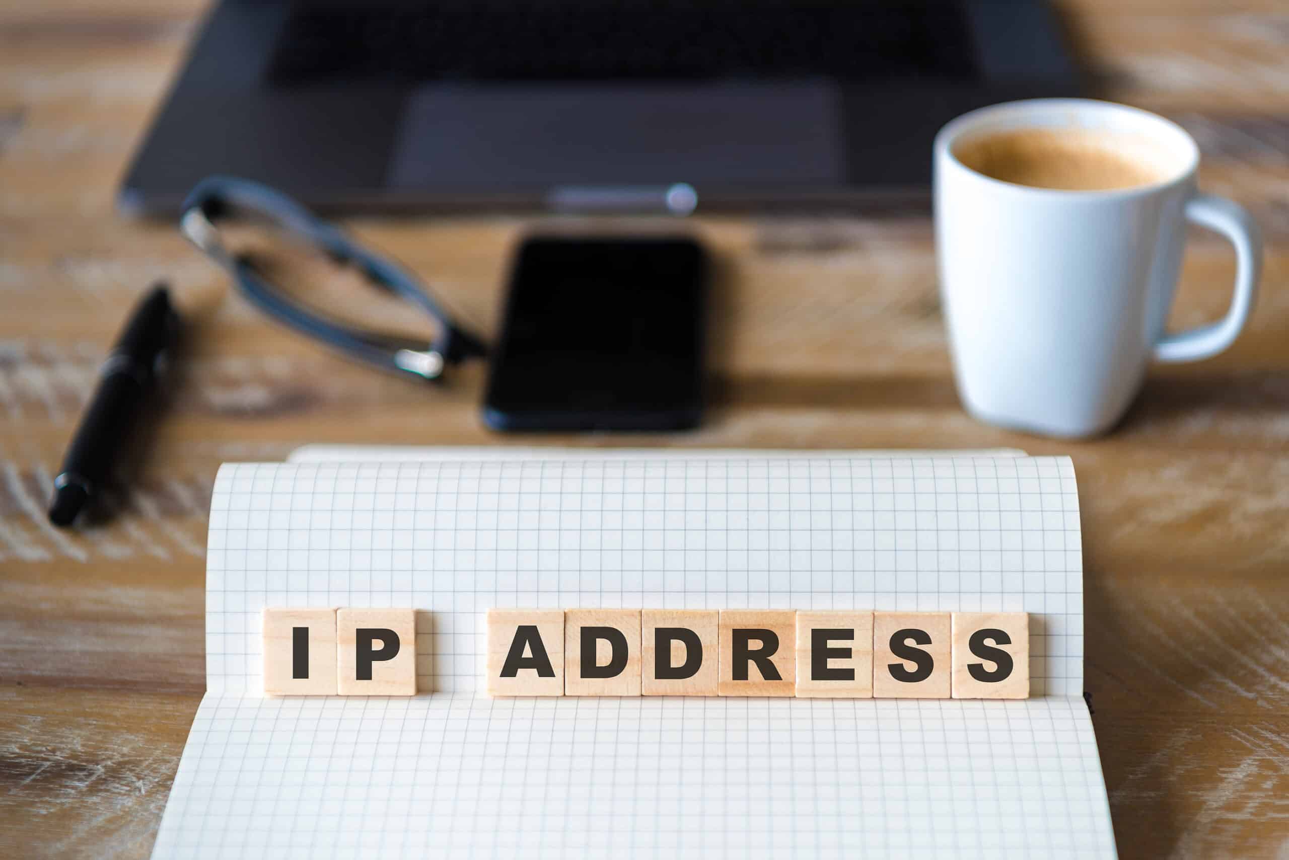 the word ip address spelled with scrabble tiles next to a cup of coffee