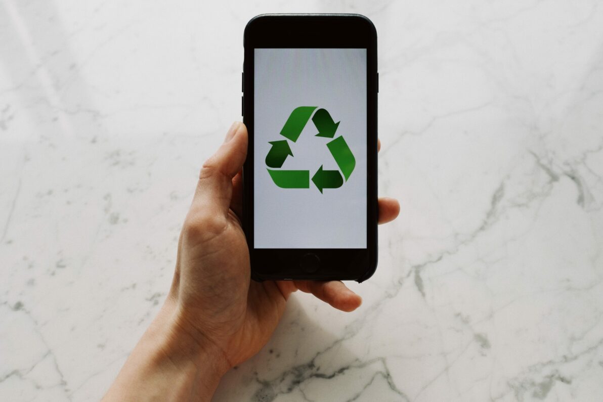 a person holding a cell phone with a recycle logo on it