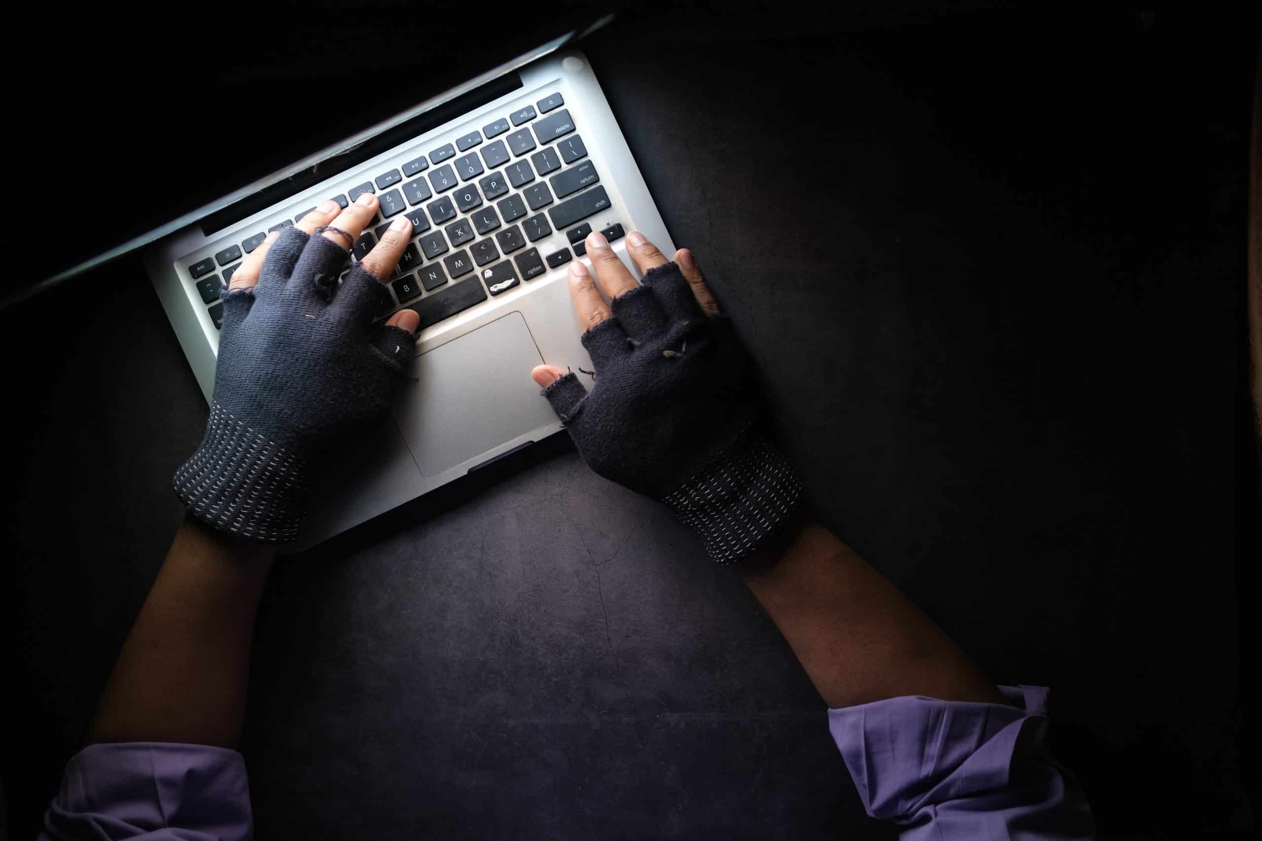 a person wearing gloves typing on a laptop