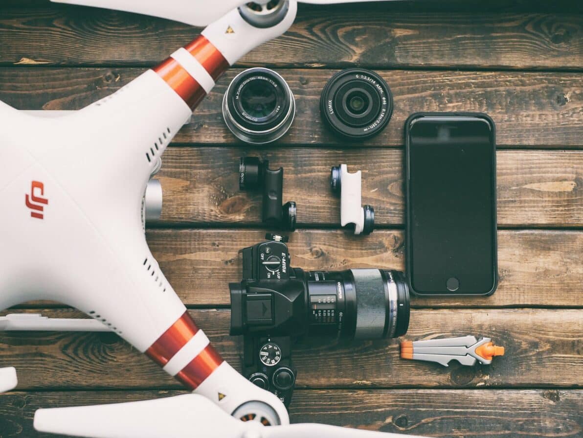 a camera, phone and other electronics on a wooden table